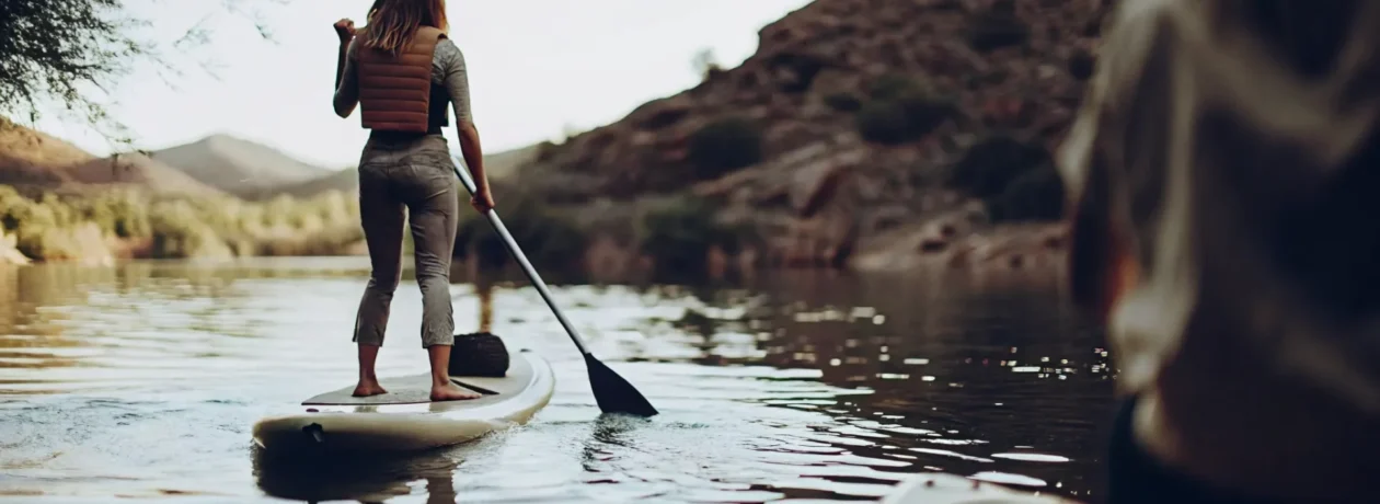 Beginner learning how to stand up on a paddle board on a calm Colorado mountain lake