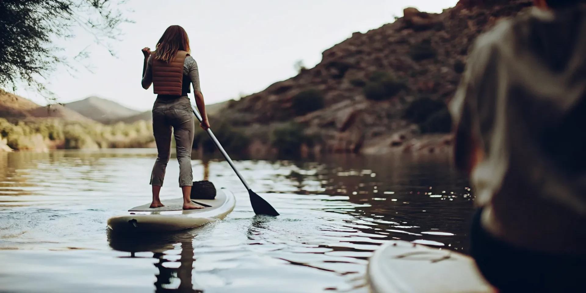 Beginner learning how to stand up on a paddle board on a calm Colorado mountain lake