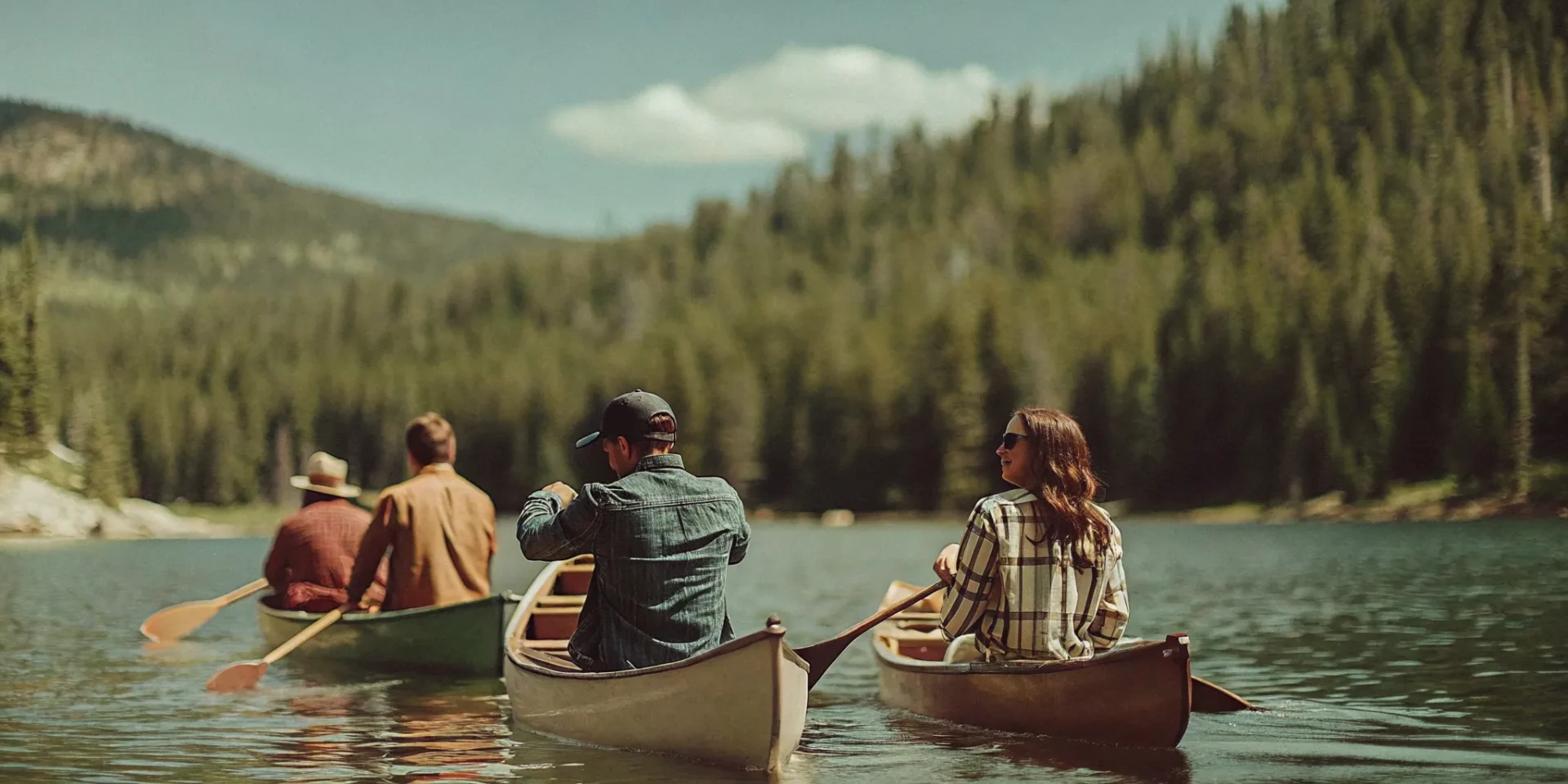 Kayakers paddling on a mountain reservoir surrounded by pine-covered peaks in Colorado