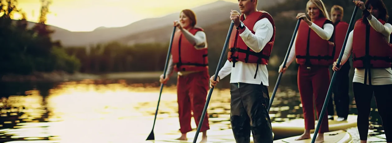Corporate group stand-up paddleboarding on calm Lake Dillon at sunrise with mountain views