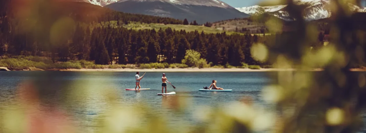 Stand-up paddleboarders and kayakers enjoying Lake Dillon with mountain peaks in background