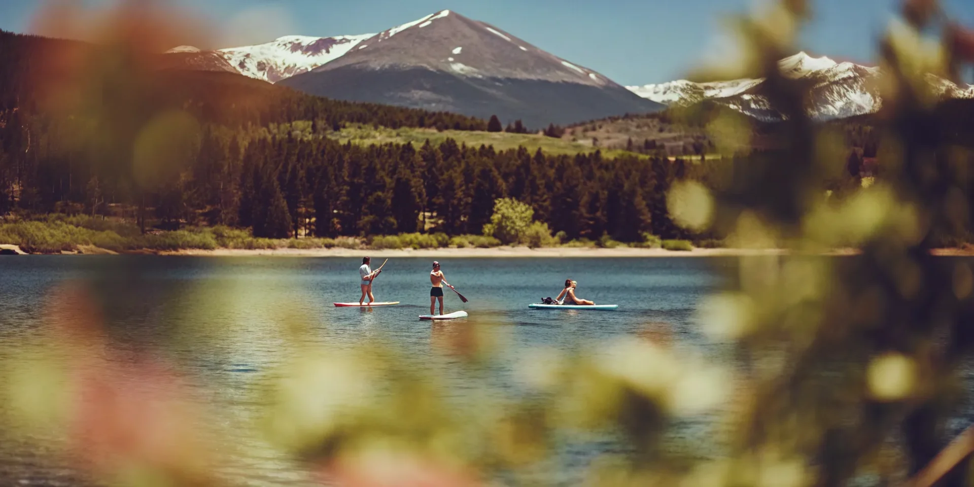 Stand-up paddleboarders and kayakers enjoying Lake Dillon with mountain peaks in background