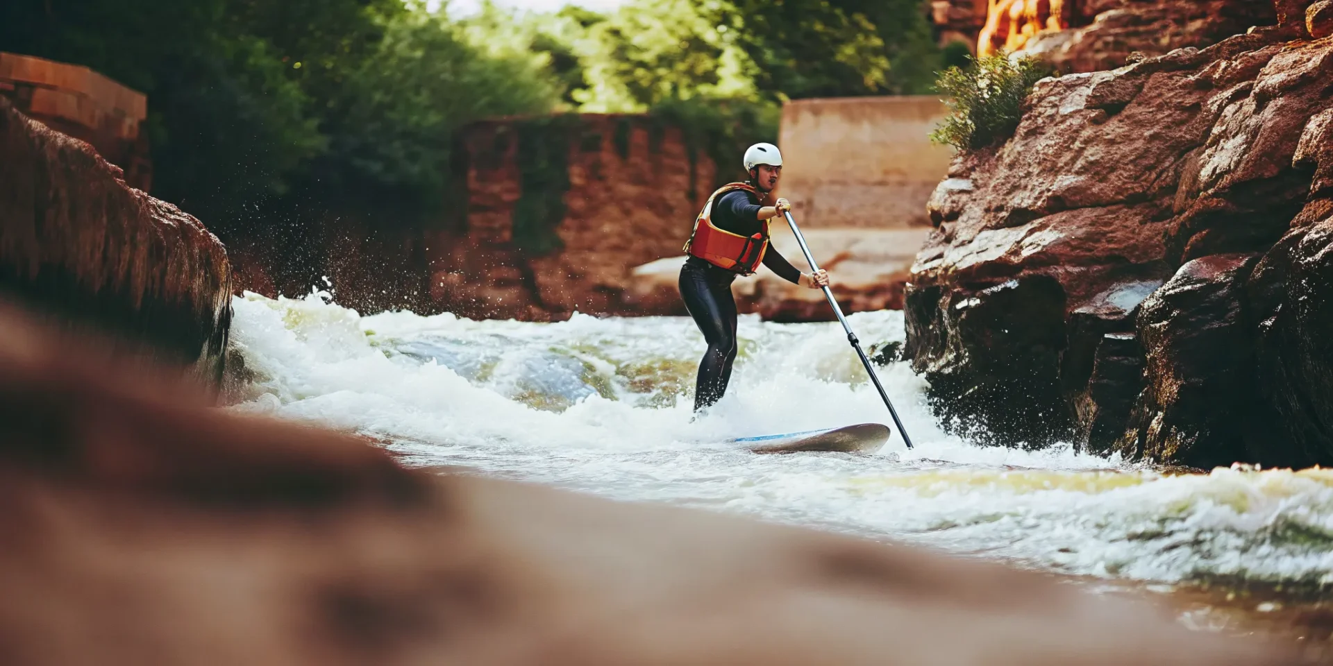 Stand up paddleboarder wearing safety gear navigating rapids on the Colorado River