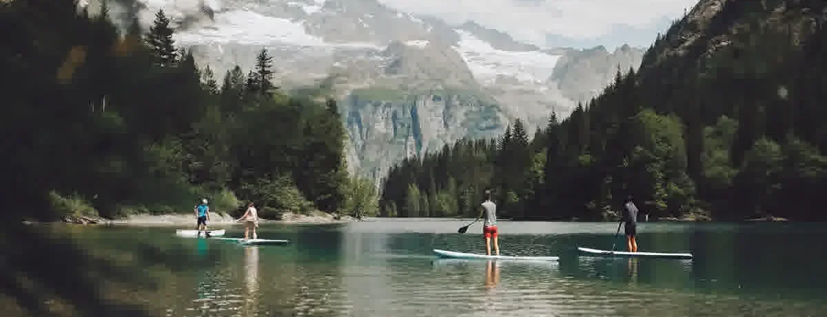 People stand-up paddleboarding on calm Lake Dillon waters with snow-capped Rocky Mountain peaks